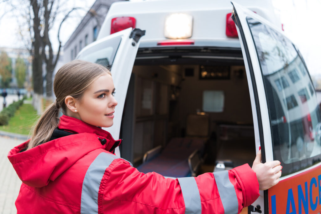 Junge Ärztin öffnet Krankenwagentüren - Tourenplanung in der ambulanten Pflege