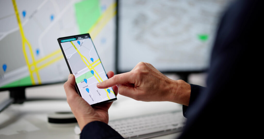 Person nutzt Navigations-App auf Smartphone mit mehreren Standortmarkierungen auf digitaler Karte